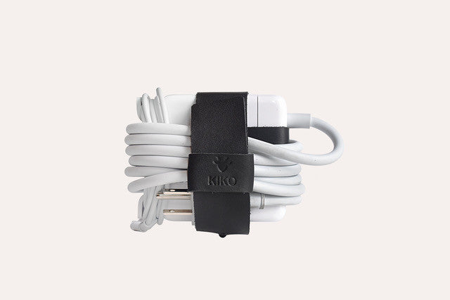 Adjustable black leather cable wrap for organizing MacBook charger cables by Kiko Leather.
