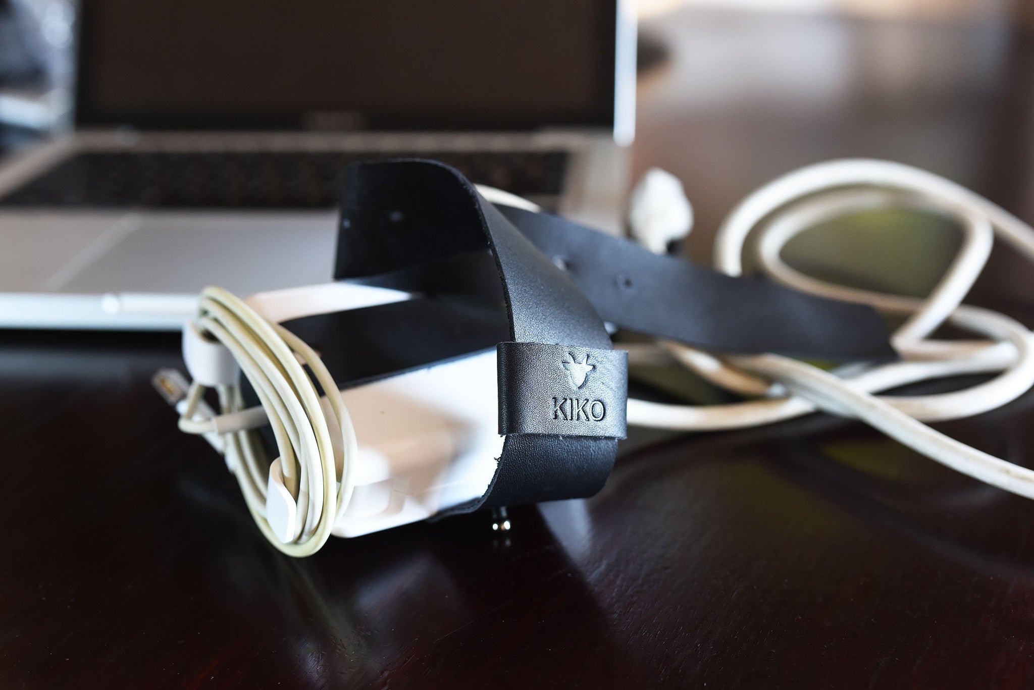 Adjustable black leather cable wrap for MacBook chargers from Kiko Leather, perfect for organized cord management.